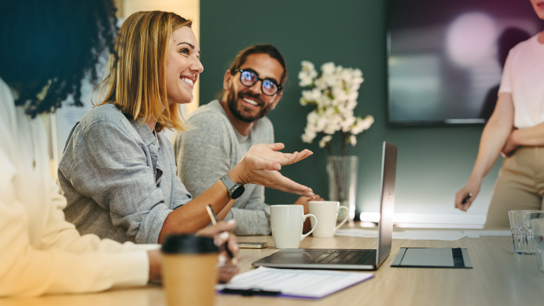 Business woman talking to her colleagues during a meeting in a boardroom. Group of happy business people working together in a creative office.